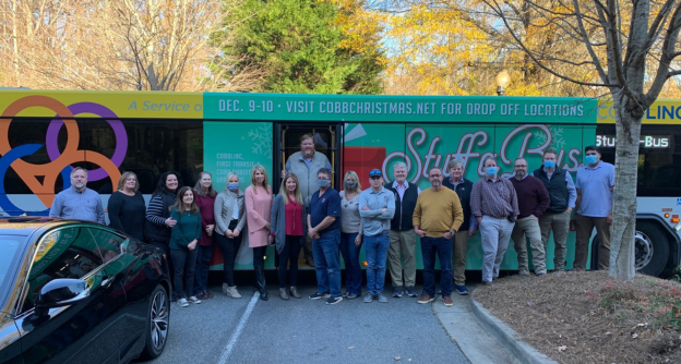 Traton Homes Cobb Christmas team collection efforts in front of Cobb Christmas bus